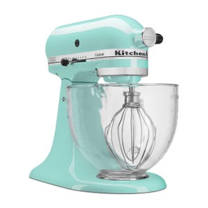 A mint green KitchenAid stand mixer featuring a clear glass mixing bowl and a metal whisk attachment, designed for various mixing tasks.