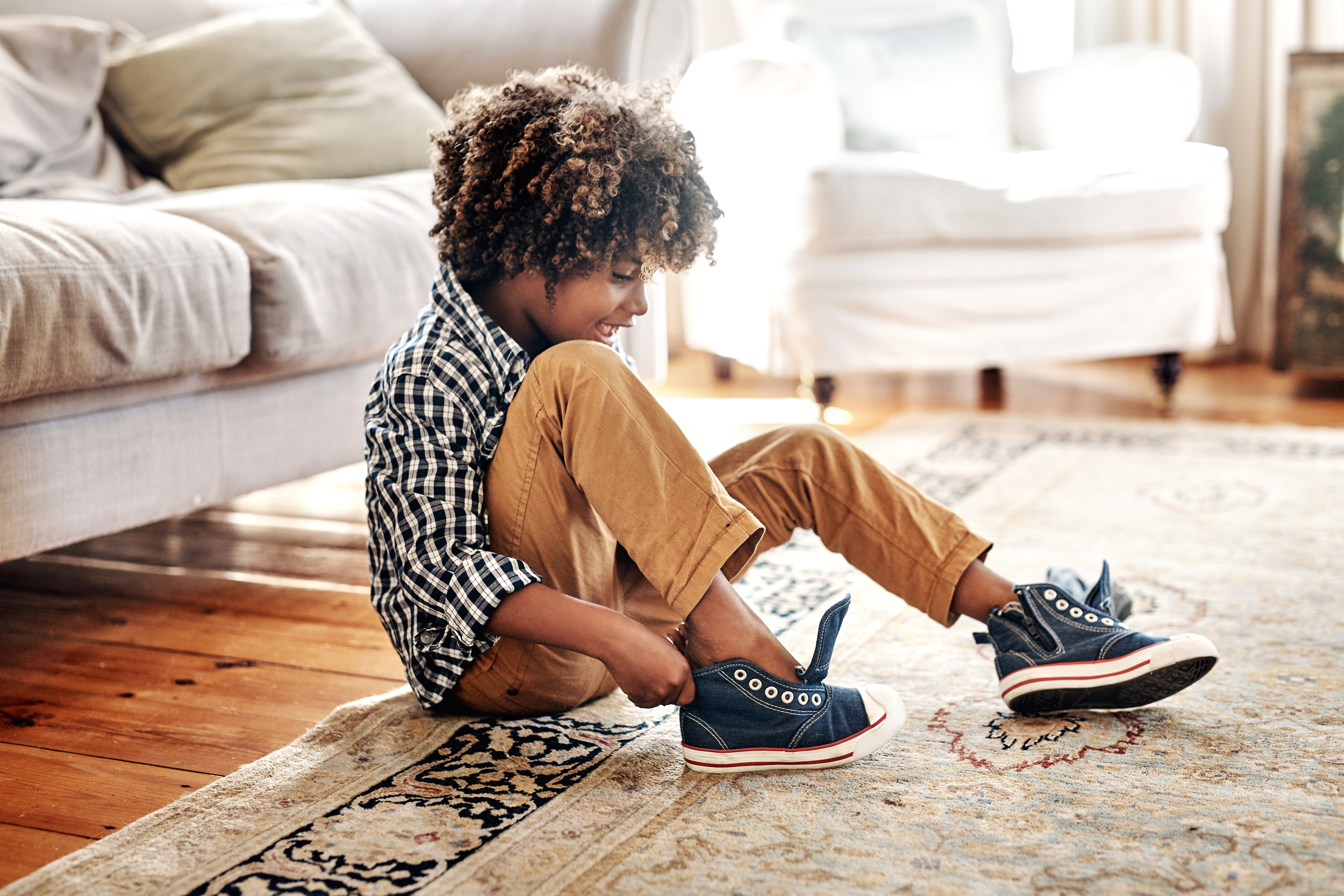 A child tying the laces of blue sneakers with white soles.