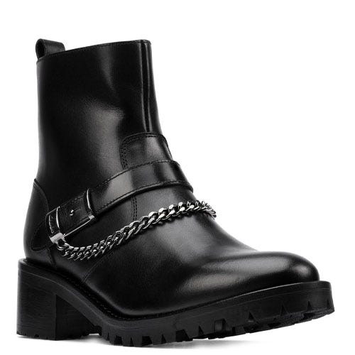 Black ankle boot with a chunky sole, featuring a decorative chain and buckle strap across the front.