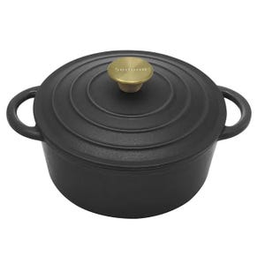 A black enamel cast-iron Dutch oven with a round shape, featuring two side handles and a lid with a brass-colored knob inscribed with \“Sedona.\“