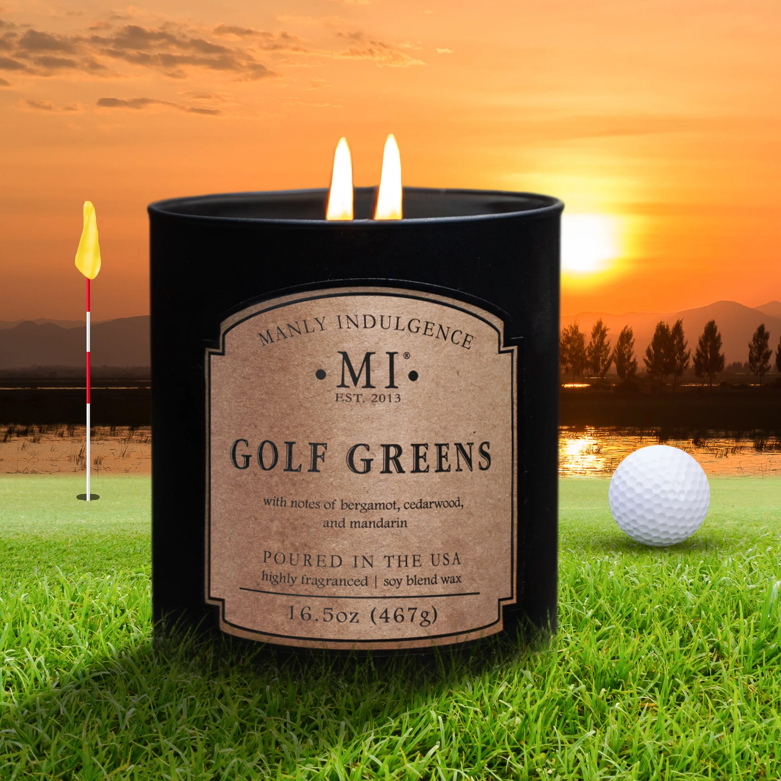 A candle labeled \“Golf Greens\“ by Manly Indulgence, featuring notes of bergamot, cedarwood, and mandarin, is set against a golf course background at sunset.