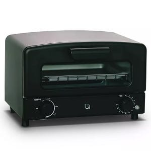 Black countertop toaster oven with a glass door, featuring temperature and timer controls on the front panel.