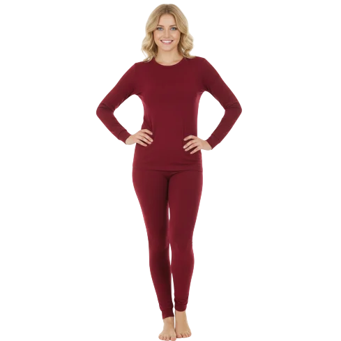 A woman is wearing a matching burgundy long-sleeve top and leggings set, standing barefoot against a plain background.