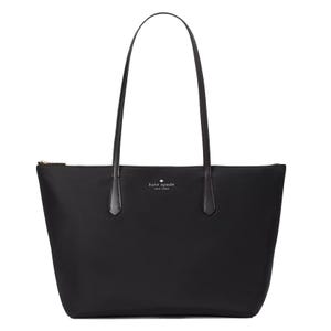 A black Kate Spade New York nylon tote with sleek design, features a zip closure, long black leather straps, and the brand's logo in silver on the front.