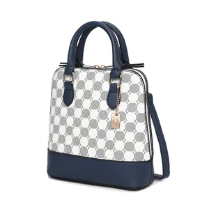 A stylish handbag featuring a blue and white pattern with blue leather accents, double handles, a detachable strap, and a gold charm with an \“M\“ initial.