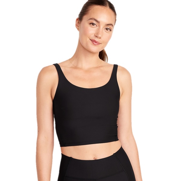 A woman is wearing a black crop tank top with thick straps, paired with black leggings.