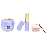 Tatcha skincare items featuring The Dewy Skin Cream, The Serum Stick, and The Kissu Lip Mask with a gold spatula, all in sleek packaging with lavender and pink tones.