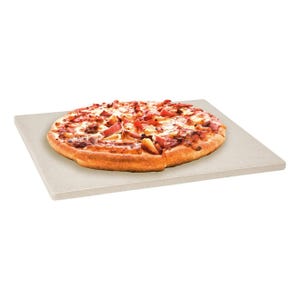 A whole pizza with pepperoni, sausage, and diced tomatoes on a square piece of cardboard.