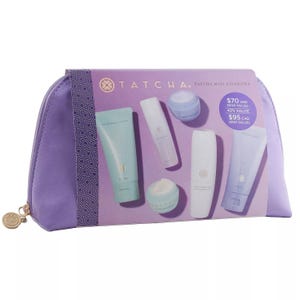 Tatcha Mini Favorites Set includes The Deep Cleanse, The Rice Wash, The Water Cream, The Essence, and Camellia Cleansing Oil, all in travel-sized containers, packaged in a purple zipper pouch.
