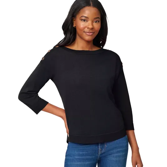 A woman wears a black sweater with button details on the shoulders and three-quarter sleeves, paired with blue jeans.