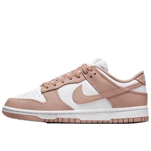 Nike Dunk Low sneakers feature a white leather upper with light pink overlays, a matching pink Swoosh, and pink laces. The shoe has a white midsole and a pink rubber outsole for a clean and stylish look.