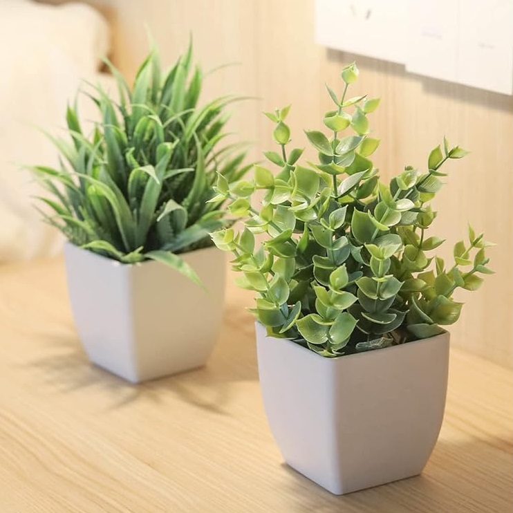 Two potted artificial succulent plants on a wooden surface.