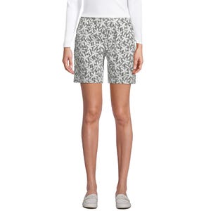 A pair of patterned shorts with a white long-sleeve top and white loafers.