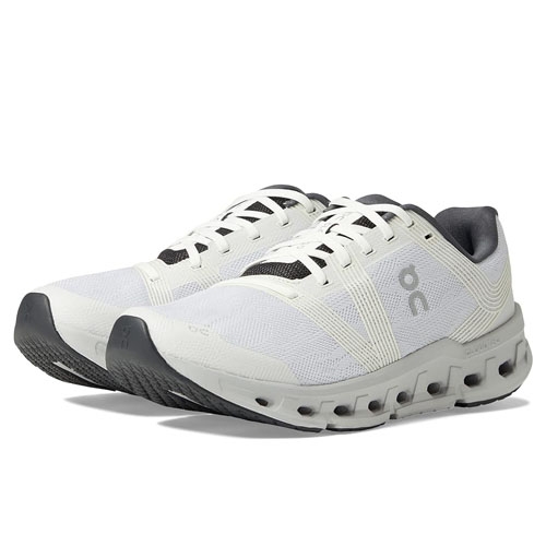 Pair of white athletic shoes with black accents and distinctive sole pattern.