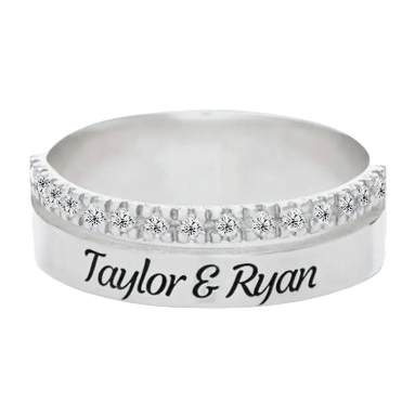 A silver ring featuring a row of small diamonds on the top half and engraved with the names \“Taylor & Ryan\“ on the band.