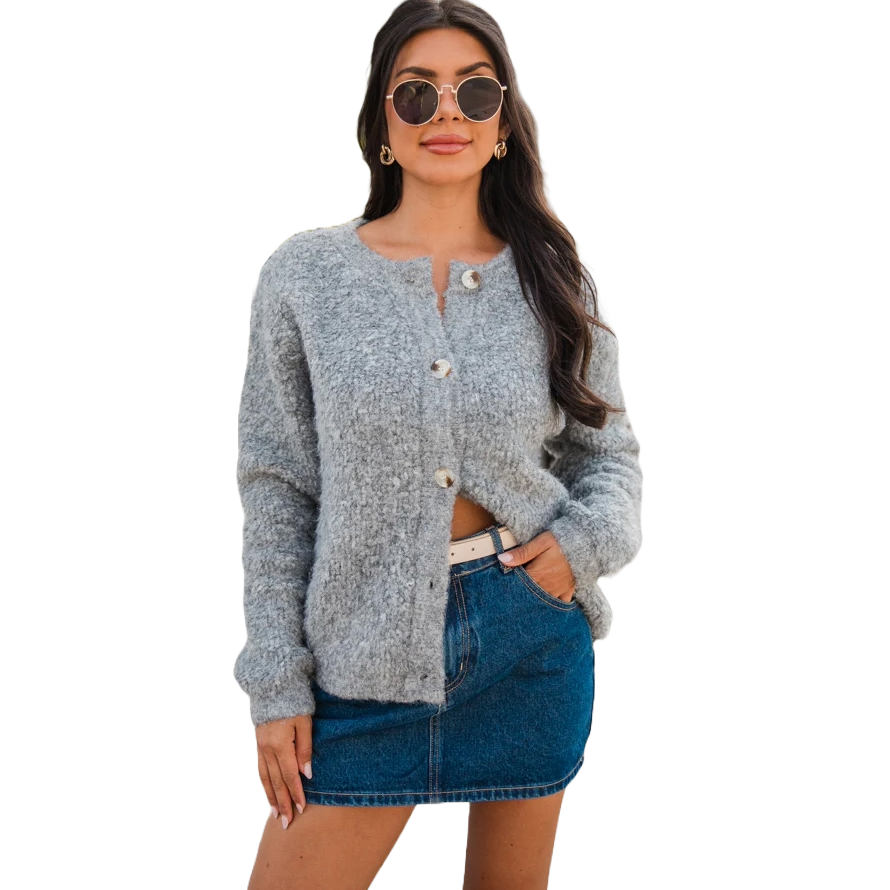 A woman is wearing a gray button-up cardigan with long sleeves and a short denim skirt, accessorized with sunglasses, earrings, and a white belt.