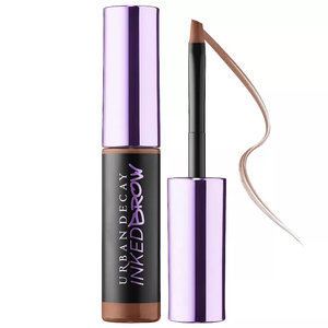 Urban Decay Inked Brow Gel features a long-lasting, smudge-resistant formula with a brush applicator, designed for filling and shaping eyebrows. The packaging is sleek with a purple cap and includes a flexible brush for precise application.