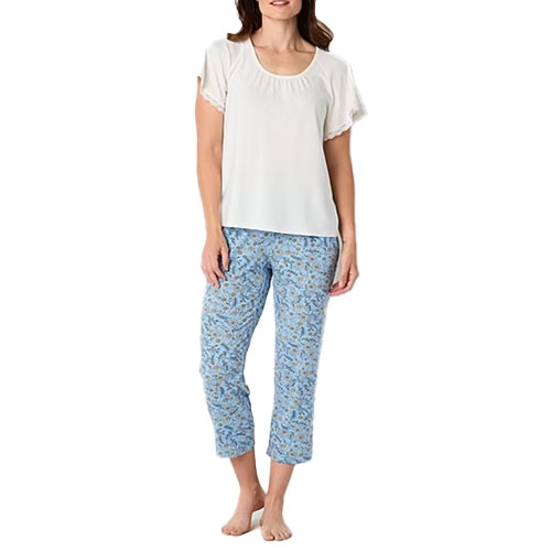 A person wearing a short-sleeved white top with blue patterned cropped pants, standing barefoot.