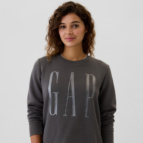 A person wearing a dark grey sweatshirt with the white GAP logo on the front.