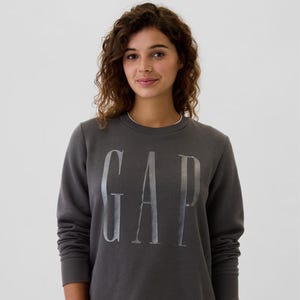 A person wearing a dark grey sweatshirt with the white GAP logo on the front.