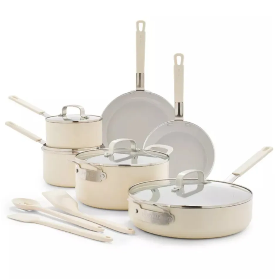 A cream-colored cookware set featuring two fry pans, a sauté pan, two saucepans, and two lids, accompanied by three kitchen utensils.