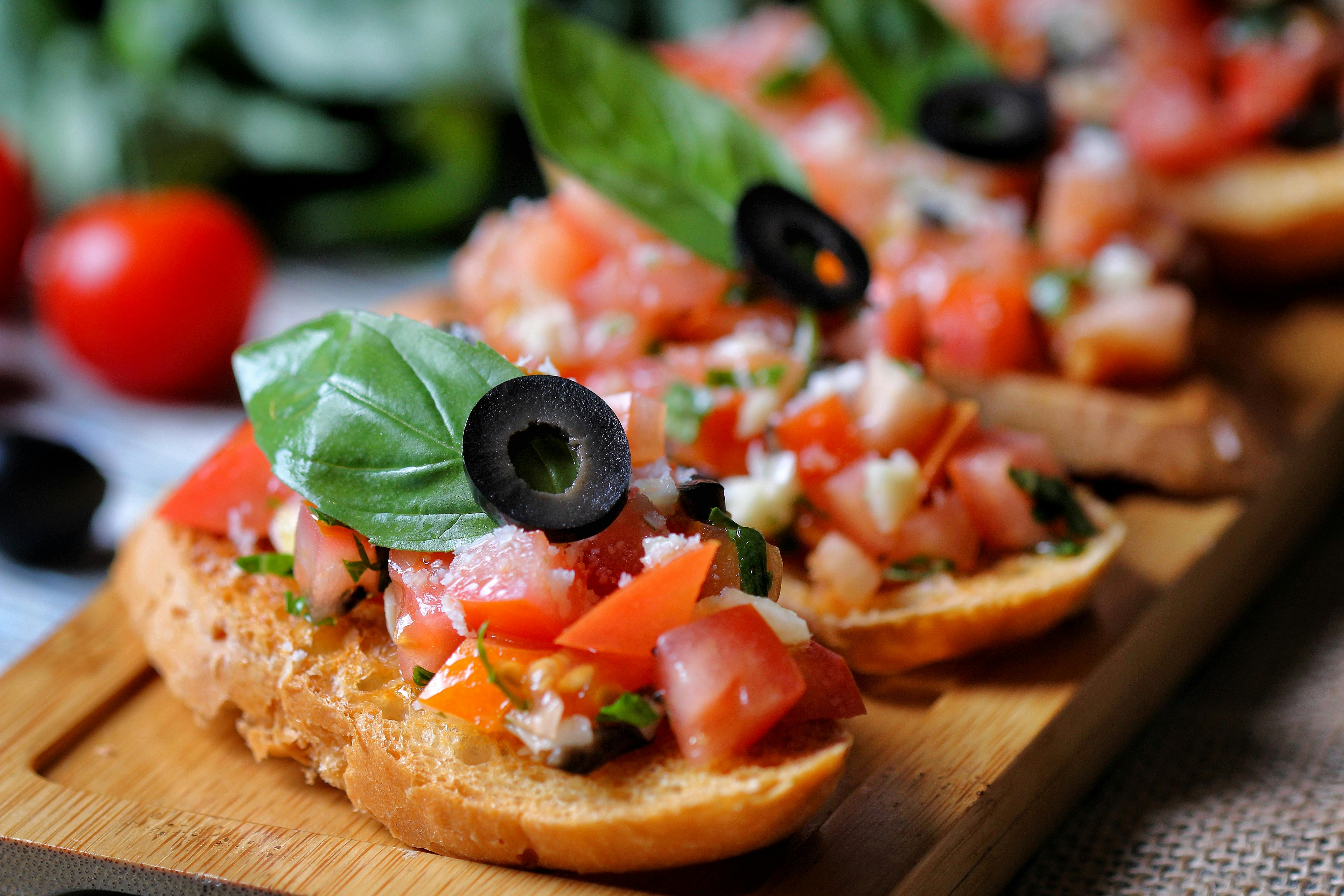 Bruschetta with diced tomatoes, black olives, and basil on toasted bread.