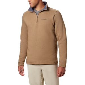 A man wears a tan Columbia Great Hart Quarter-Zip Pullover featuring a contrasting gray inner collar, embroidered logo on the chest, and long sleeves. It's paired with light-colored pants and is designed for casual or outdoor wear.