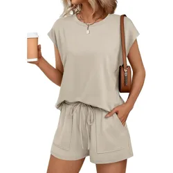 A woman wearing a casual beige short-sleeve top and matching drawstring shorts, accessorized with a brown shoulder bag and necklace, holding a coffee cup.