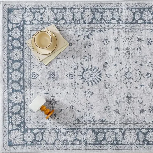 Decorative area rug with a traditional floral pattern in blue and white, paired with a stack of books, yellow and beige decorative bowls, and a small orange and white object displayed on top.
