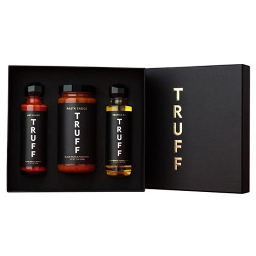 Three bottles of Truff sauces and oil, including a hot sauce, pasta sauce, and truffle oil, are displayed in an elegant black gift box with the brand name in gold letters.