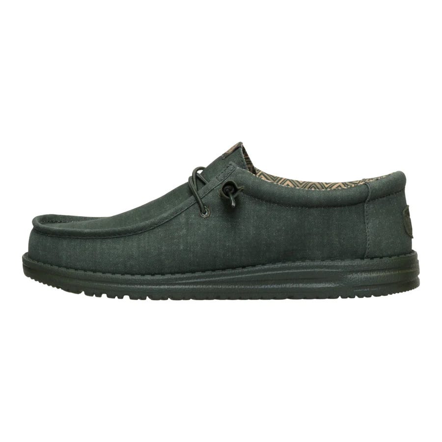 A casual, dark green slip-on shoe with a textured sole and patterned interior, featuring a moccasin-style design and lace accents.