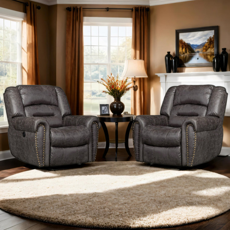 Two oversized power recliners with USB ports feature plush, textured gray upholstery and brass nailhead trim. They are positioned on a round beige rug, framed by curtains and a side table with a lamp and decor.