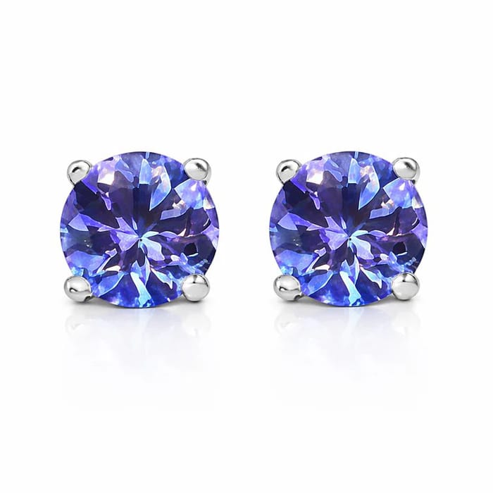Pair of round-cut, blue-purple gemstone stud earrings set in silver prongs, reflecting light with a vibrant sparkle.