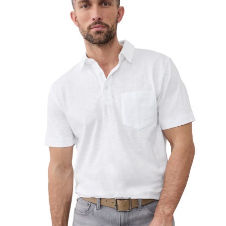 A man is wearing a white short-sleeve polo shirt with a front pocket, paired with light gray pants and a brown belt.