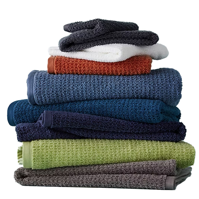 A stack of six colorful bath towels in shades of grey, green, blue, and orange, designed for quick drying.