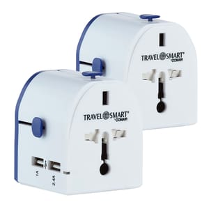 2-pack universal travel adapters with dual USB ports (1A and 2.4A) compatible with various plug types. White with blue accents, branded \“Travel Smart by Conair.\“