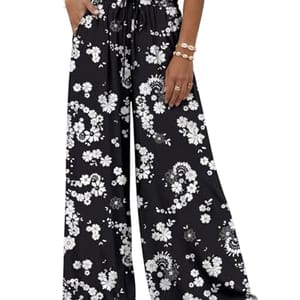 Wide-leg black pants with a white floral pattern, featuring an elastic waistband and drawstring, paired with a white sleeveless top.