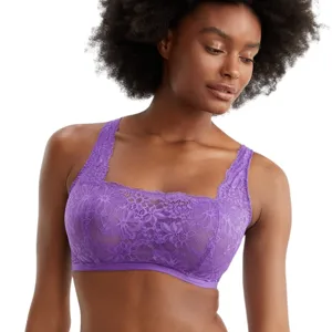 A woman is wearing a matching set of purple lace lingerie, featuring a bralette and briefs, with floral patterns.