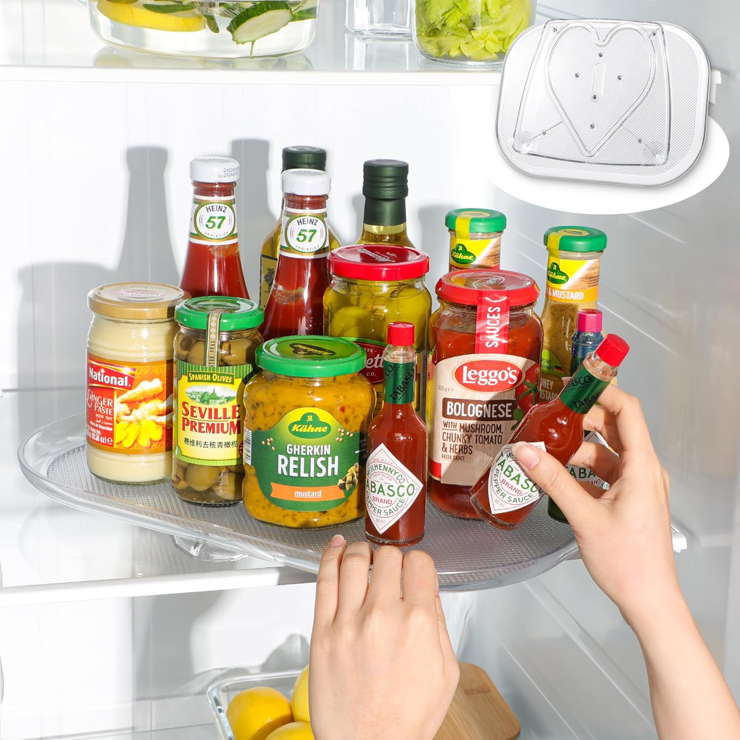 Various condiments, including Tabasco sauce, Leggo's Bolognese, Heinz ketchup, and Kühne gherkin relish, are arranged on a fridge tray next to lemons and herbs.