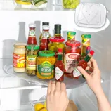 Various condiments, including Tabasco sauce, Leggo's Bolognese, Heinz ketchup, and Kühne gherkin relish, are arranged on a fridge tray next to lemons and herbs.