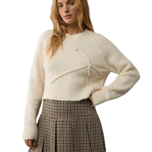 Cream-colored, cropped crew neck sweater with a decorative bow detail on the front, paired with a pleated plaid skirt.