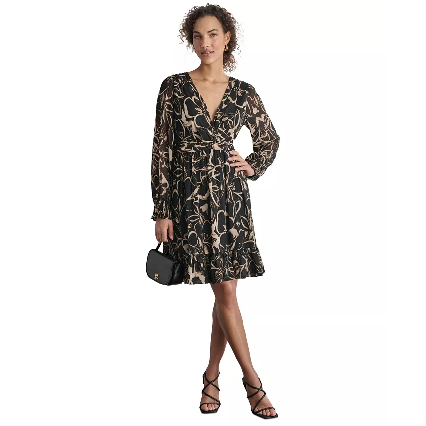 A woman wearing a black floral print dress with long sleeves, strappy black sandals, and carrying a small black shoulder bag.