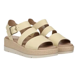 Beige open-toe sandals with wide straps and a low wedge heel, featuring a buckle closure and textured sole.