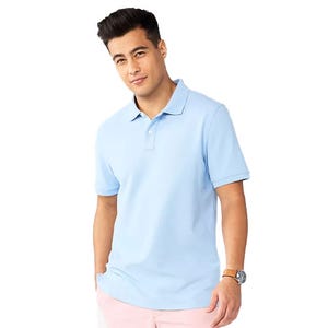 A man wears a light blue polo shirt and pink pants, accessorized with a watch.