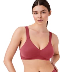 A woman is wearing a seamless, unlined bralette in a deep rose color with adjustable straps and a scoop neckline.