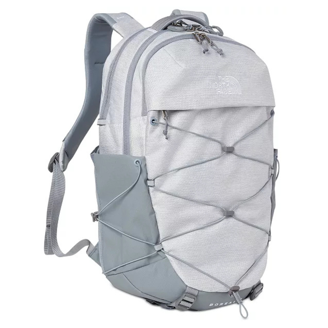 A light gray backpack from The North Face with bungee cord detailing on the front, side pockets, and padded straps, suitable for travel or daily use.