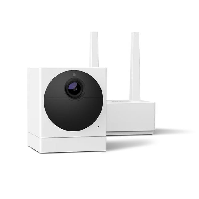 A white, cube-shaped security camera paired with a base station featuring dual antennas, often bundled with a subscription for enhanced features.