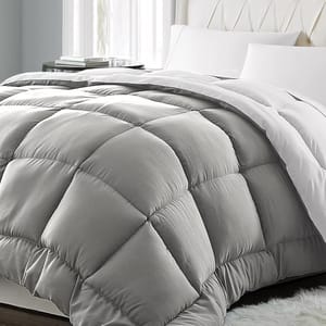 A gray, quilted comforter with a plush, diamond-pattern design is placed on a bed with white pillows and sheets.