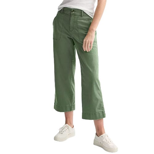 A person is wearing green wide-leg cropped pants with large front pockets, paired with a white shirt and white sneakers.