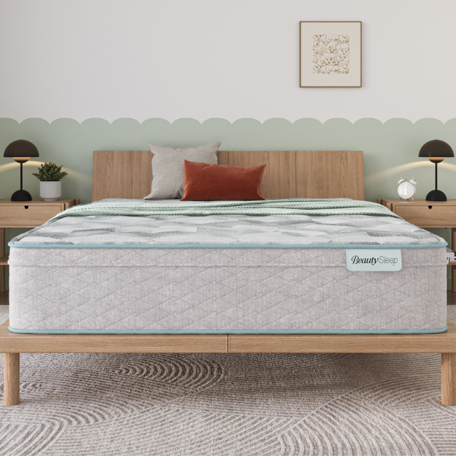 A mattress labeled \“BeautySleep\“ on a wooden bed frame, accompanied by three decorative pillows, stands in a bedroom with light wood nightstands, modern lamps, and a patterned rug.
